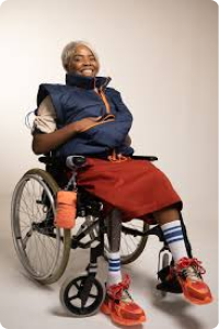 Woman in wheelchair with a prosthetic wears a navy blue gillete with orange zip